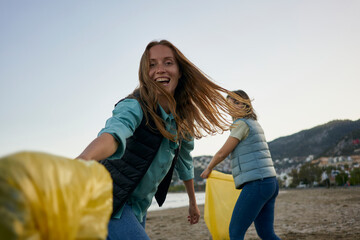 Cheerful volunteers having fun holding garbage bags at beach