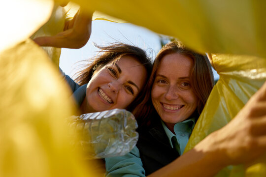 Happy volunteers looking in plastic garbage bag