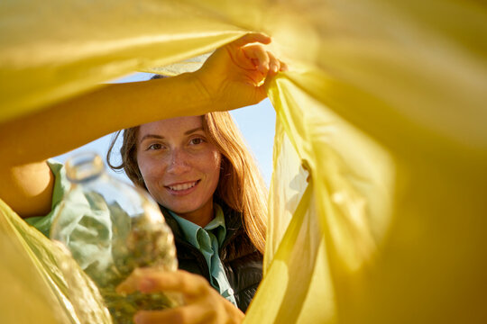 Smiling woman looking inside yellow garbage bag