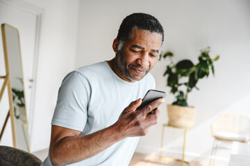 Mature man using mobile phone at home
