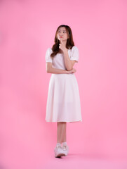 full body image of asian woman in skirt posing on pink background