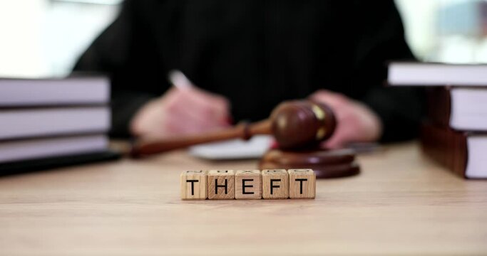 Word theft on wooden cubes on judge table near gavel closeup 4k movie slow motion. Criminal liability for theft concept 