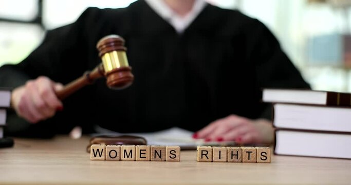 Judge knocking gavel on background of words women rights closeup 4k movie slow motion. Freedom or women equality concept 