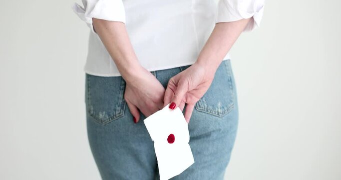 Woman holding onto rectal area with bloody toilet paper back view 4k movie slow motion. Bleeding as complication and symptom of hemorrhoids and colorectal cancer concept