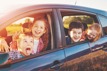 Group of cute children sitting in the car and and looking out through the car windows