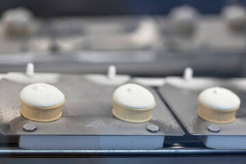 Icecream automatic production line - conveyor belt with ice cream cones at modern food processing factory. Food dairy industry, manufacturing, engineering and automated technology equipment concept