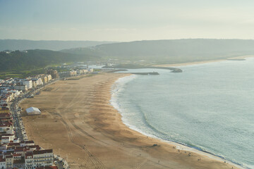 View Nazare beach riviera with cityscape of Nazare town at sunny weather. Portugal. High quality photo