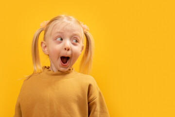 Surprised little blonde girl with two ponytails. Portrait of child with sly look. Copy space.