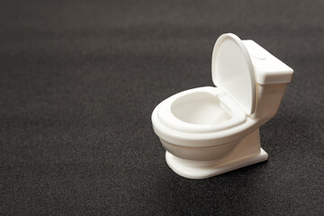 Toy white toilet bowl on grey background. Small toilet bowl. Copy space. Macro shot. Space for text