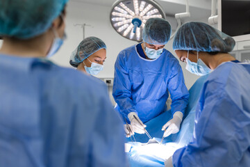 Team of Professional surgeon, Assistants and Nurses Performing Invasive Surgery on a Patient in the Hospital Operating Room. Surgeons Talk and Use Instruments. Real Modern Hospital.