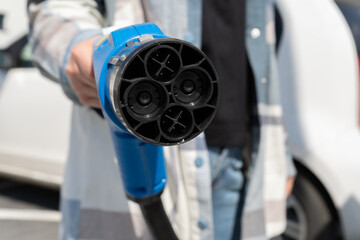 Woman holding fast charging socket CHAdeMO. Connector plug for electric vehicles battery at EV car charging station, direct current DC. Female hand plugging in charger into electric car.