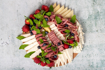 Antipasto set plate. Cold smoked meat plate. Antipasto with ham, prosciutto, salami, blue cheese, mozzarella with blueberries and strawberries. Top view
