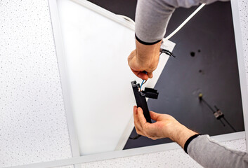 Close-up of a male electrician installing a ceiling lamp repairing and connecting cables