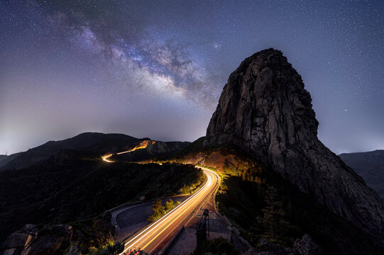 Night time image of impressive rock landscape with illuminated curved road and milky way galactic core on the Spanish canary island of La Gomera 