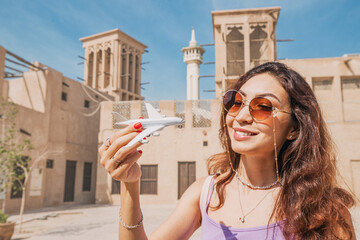 Girl with toy airplane in old town Bur Dubai or Al Fahidi district. Air transport ticket prices and travel concept.