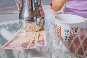A girl customer leaves a tip in the dirham aed on a table in a cafe with Arabic coffee