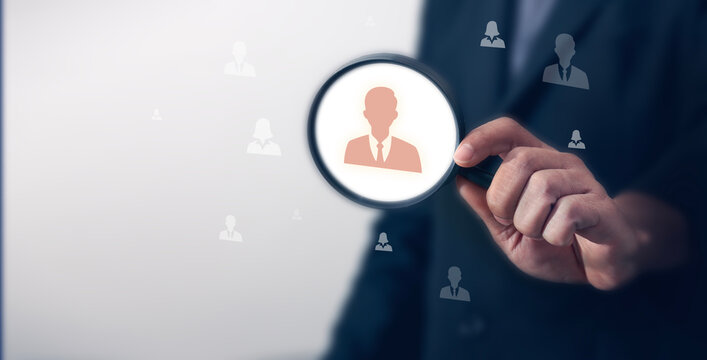 Businessman using magnifying glass to search human virtual icons for leadership development, recruitment and prospecting concept, HRM or Human Resource Management. Selection. Selection.
