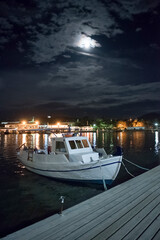 Porto Rafti town. Night illumination, reflections of buildings and small fishing boat in the  marina. Greece.