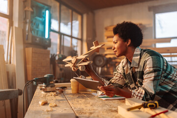 Female designer creating wooden toy in workshop.