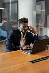 Portrait of successful businessman in office. Young smiling man talking to the phone..