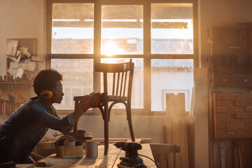Female carpenter refurbishing chair.