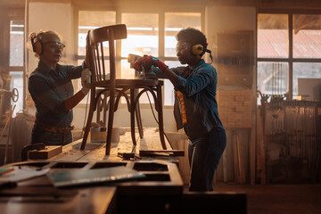 Workers in wood workshop refurbishing furniture.