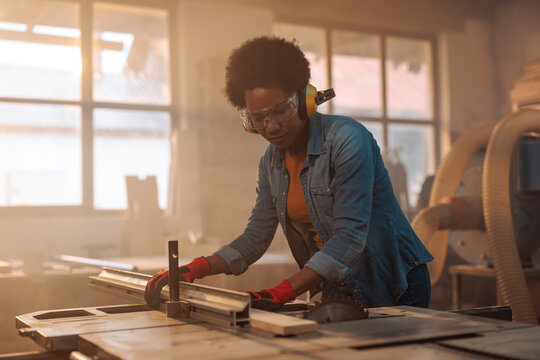 Woman using table saw.