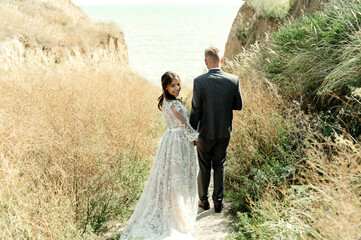 insanely happy wedding couple having fun on the wild beach. newlyweds walk holding hands. happy young marriage