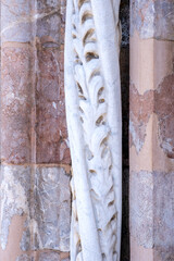 Marble details on facade of Messina Cathedral or Duomo di Messina, Sicily, Italy. Carved stone columns and reliefs, pink marble wall. Decorative elements in architecture