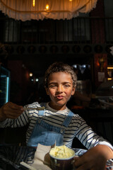 Portrait of African American boy eating ice cream in a restaurant.