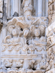 Fototapeta na wymiar Marble details on facade of Messina Cathedral or Duomo di Messina, Sicily, Italy. Reliefs on wall picturing figures of Saints. Decorative elements in architecture