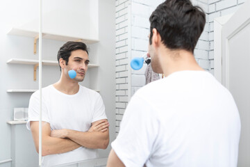 Handsome man standing in front of the mirror and doing facial massage with vacuum cups. Skin care and healthy lifestyle concept