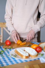 Aged woman cuts fresh vegetables for healthy sandwiches