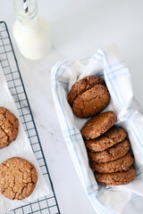 Freshly baked healthy vegan cookie on a cooling rack stand on a table next to milk. View from