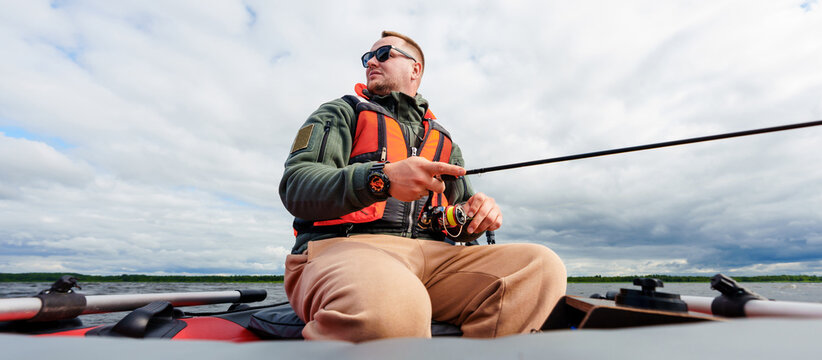 Banner, panoramic photo. A professional fisherman catches a fish from a boat