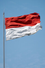 Naklejka na ściany i meble Red and white, Indonesian flag on the wind in the blue sky