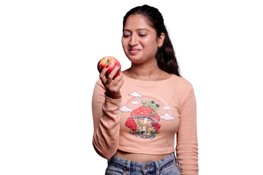 PNG of a Girl Looking and holding at Red Apple. A close-up shot of a young girl holding an organic red apple and looking at it with curiosity isolated on a transparent PNG background