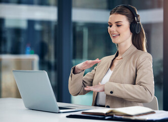 Presenting her ideas in detail. Shot of a young businesswoman wearing headphones while having a video call on a laptop in an office.