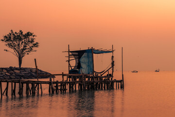Blurred nature background of the morning sun by the sea, a beautiful golden light, among the trees, rocks and local fishing boats, the beauty of nature during the day.