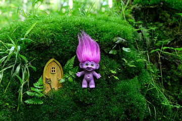 cute tale troll and little wooden door in mystery forest, natural green background. funny troll toy...