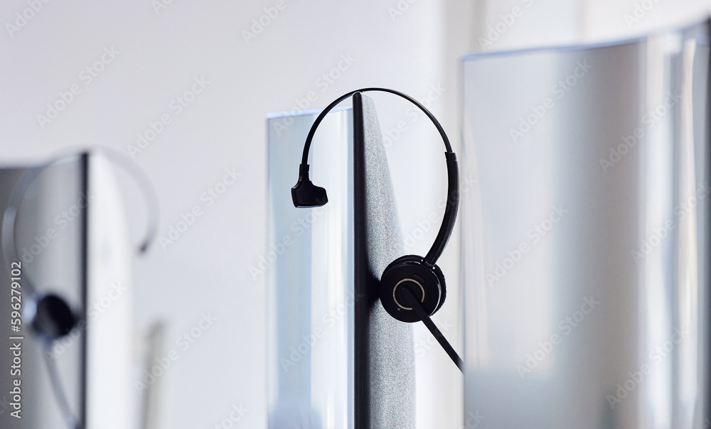 Poster We are unavailable right now, be try again later. Closeup shot of a headset resting on a computer monitor in a call centre.