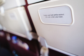 Fasten your seat belt while sitting. and a life jacket under your seat Message behind seat backrest