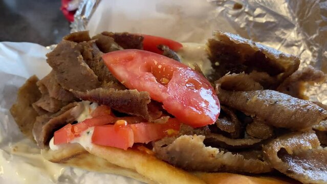 Lamb gyro with tomato slices served at a restaurant in Fort Wayne, Indiana with close up video.