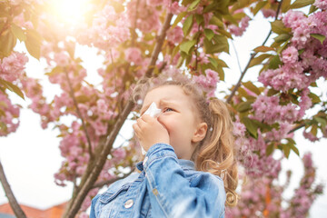 Fototapeta premium The child wipes his nose with a napkin. Seasonal allergy to flowers.