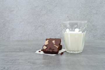 Brownies and milk glass on stone texture background. Chocolate brownie with sliced almond nuts toppings. Chocolate Brownie pieces. selective focus.