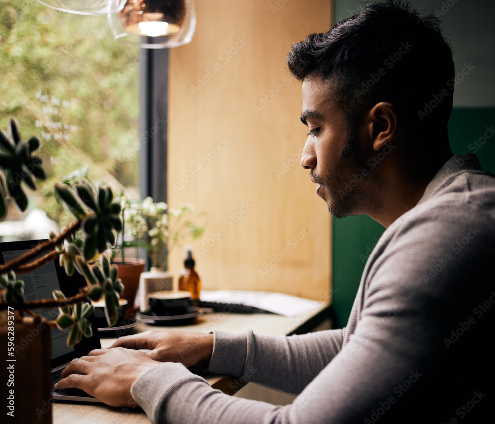 Poster young mixed race man or student browsing on a laptop in a cafe. one indian guy studying or working f