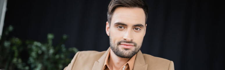 Obraz premium young successful businessman smiling at camera in office, banner.