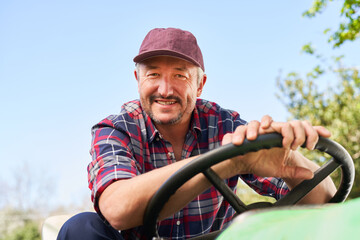 Smiling male farmer driving green tractor on sunny day