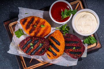 Vegan beetroot carrot cutlets. Vegetable grilled cutlets with ketchup and mayo sauces, summer bbq party food, burgers ingredient, black concrete background copy space