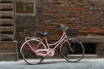 Fototapeta na wymiar Una bicicleta aparcada contra un muro de ladrillo en una calle de Lucca, Italia.